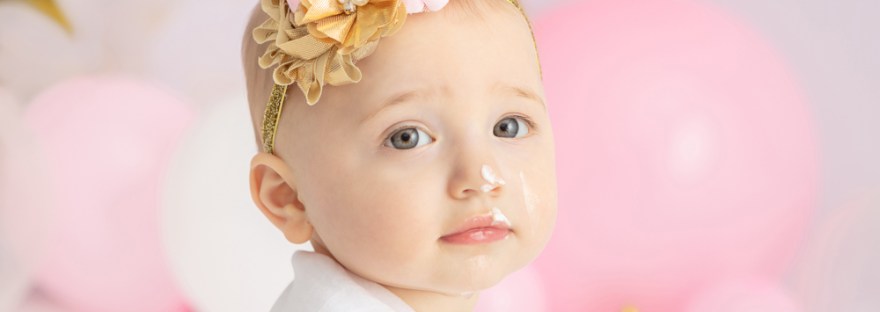 one year-old girl with gray eyes looking seriously at the camera, 1st birthday cake smash session