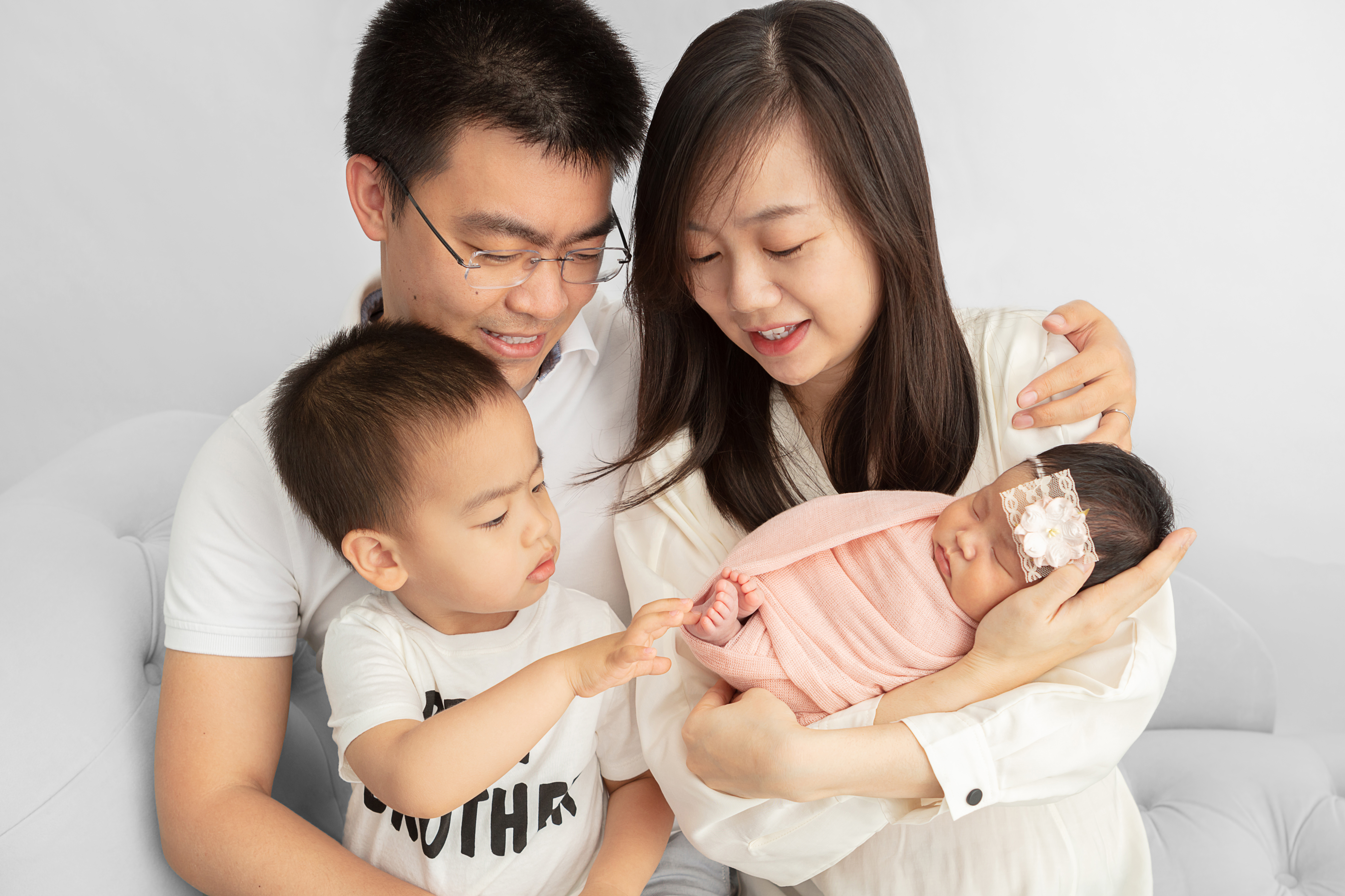 big brother being introduced to his new baby sister with their parents looking down at them