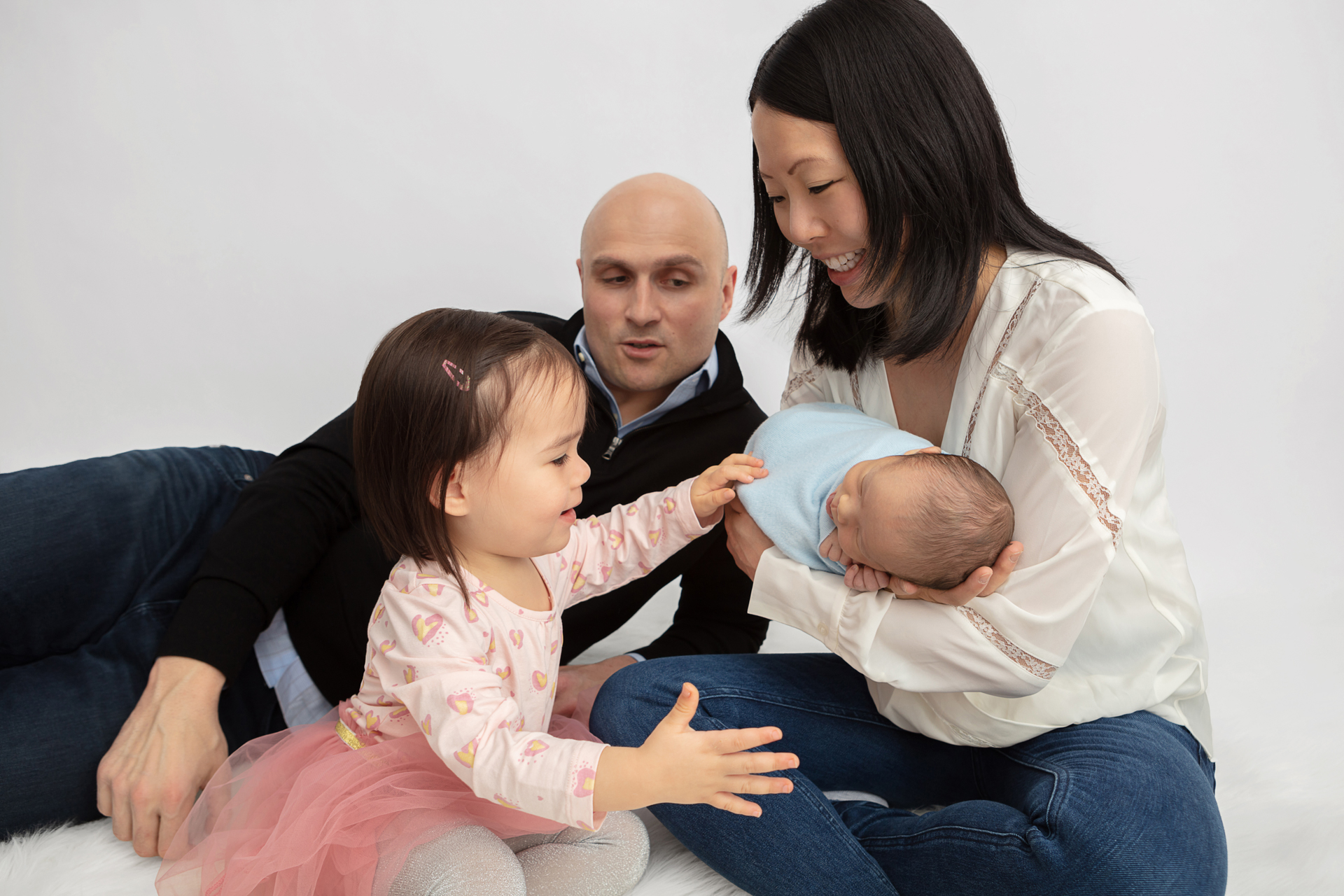 new family of four playing together on the studio floor of Looking Up Photography