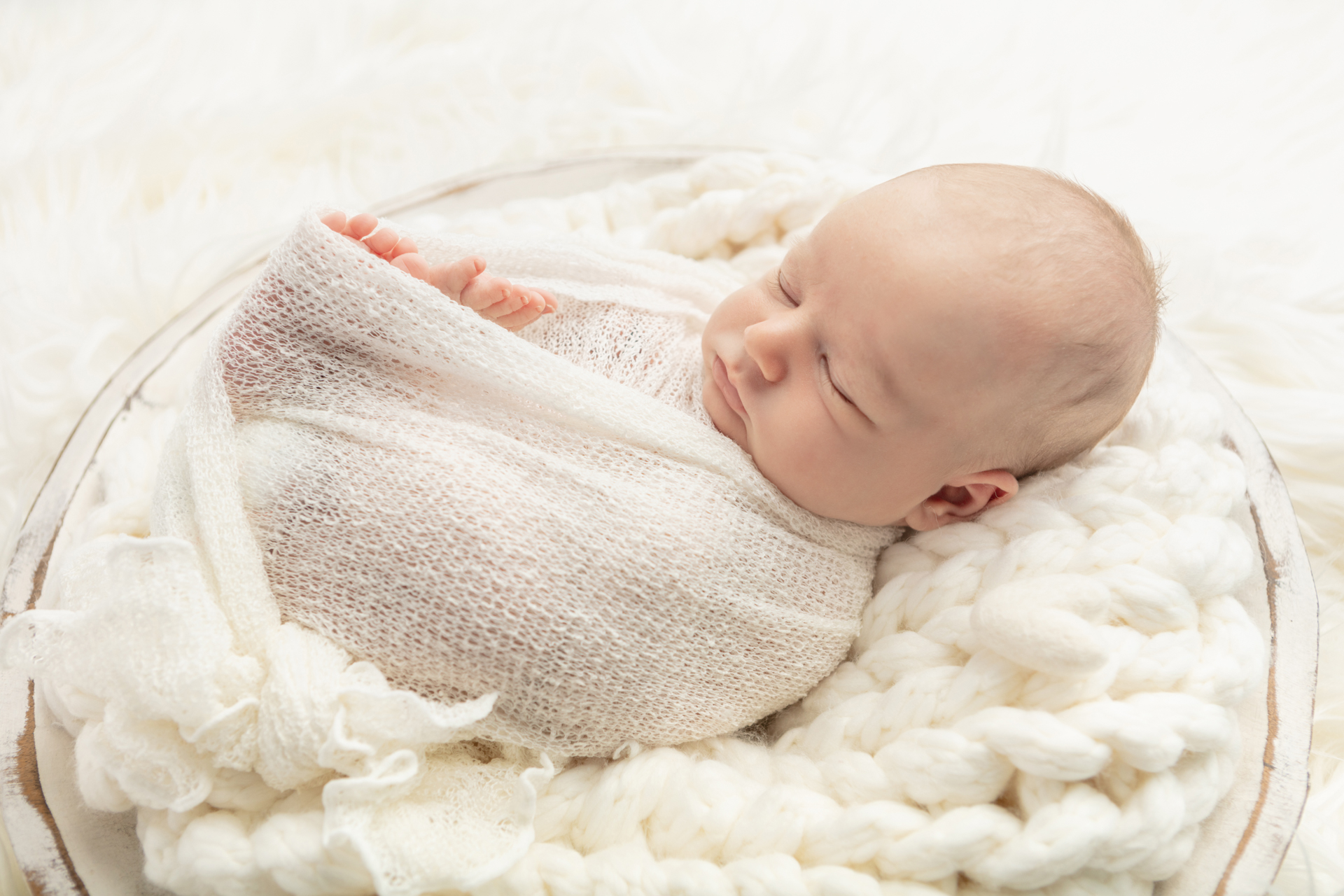 Looking Up Photography; loosely swaddled newborn boy photographed with ivory blankets