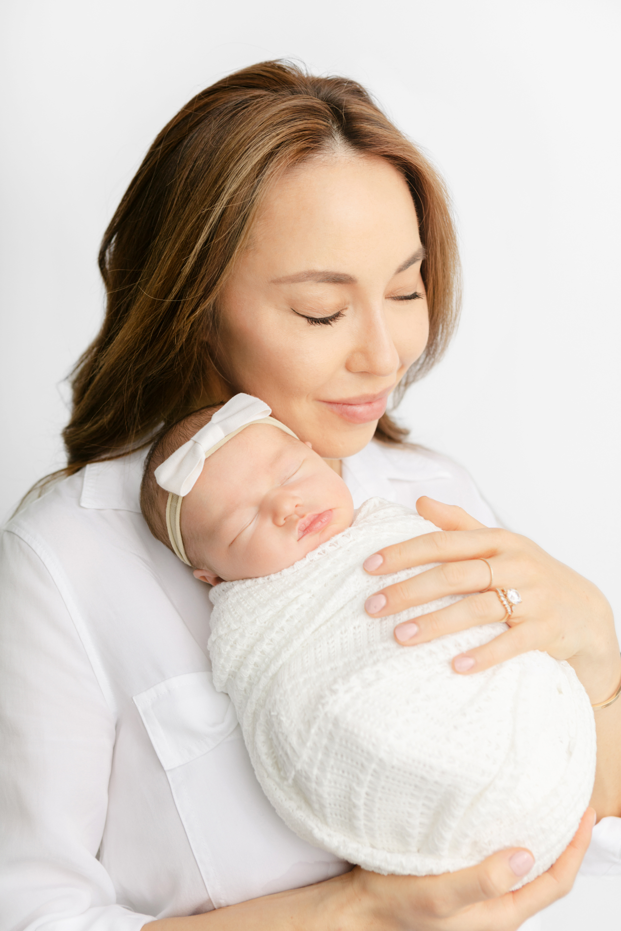 new mother peacefully holding her swaddled newborn baby girl and closing her eyes